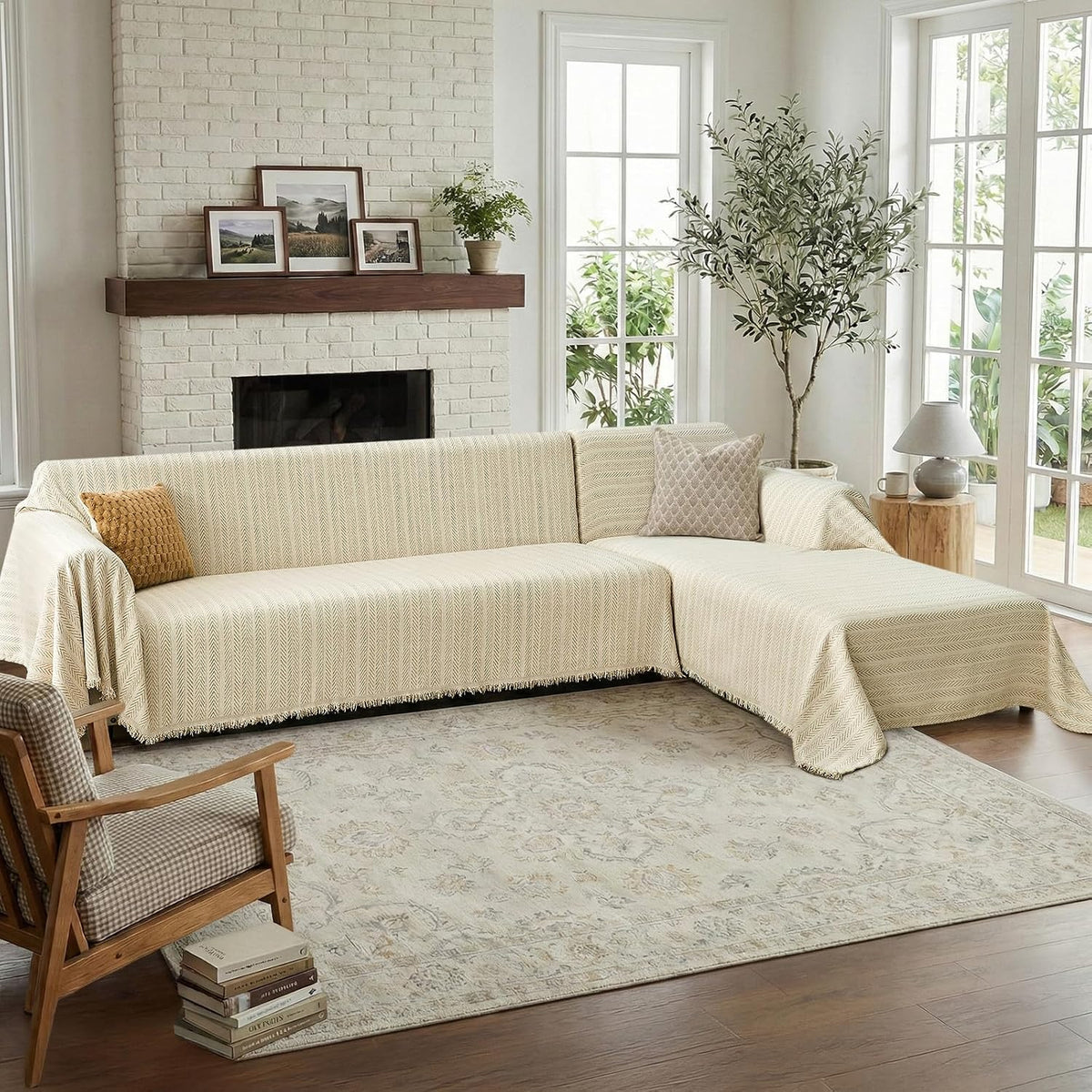 L-shaped sectional covered in a herringbone throw in a warm living room with brick fireplace and plants.
