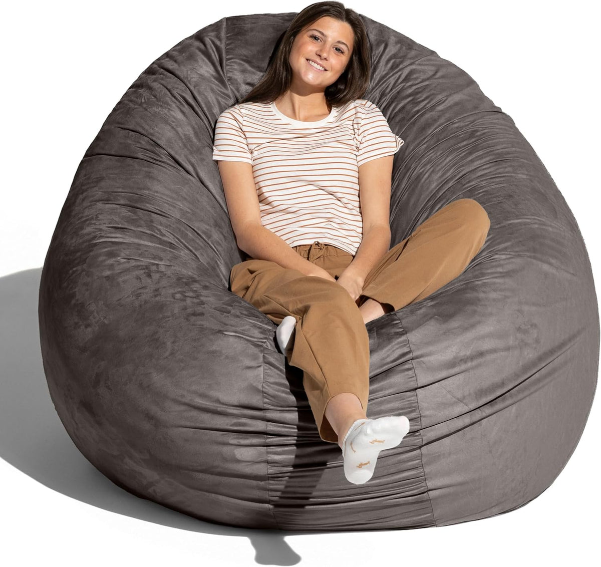 Woman reclining in a large charcoal gray bean bag on a white background.