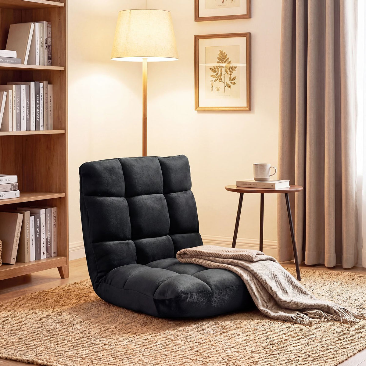 Black padded floor chair on a woven rug beside a bookcase, lamp and small table.