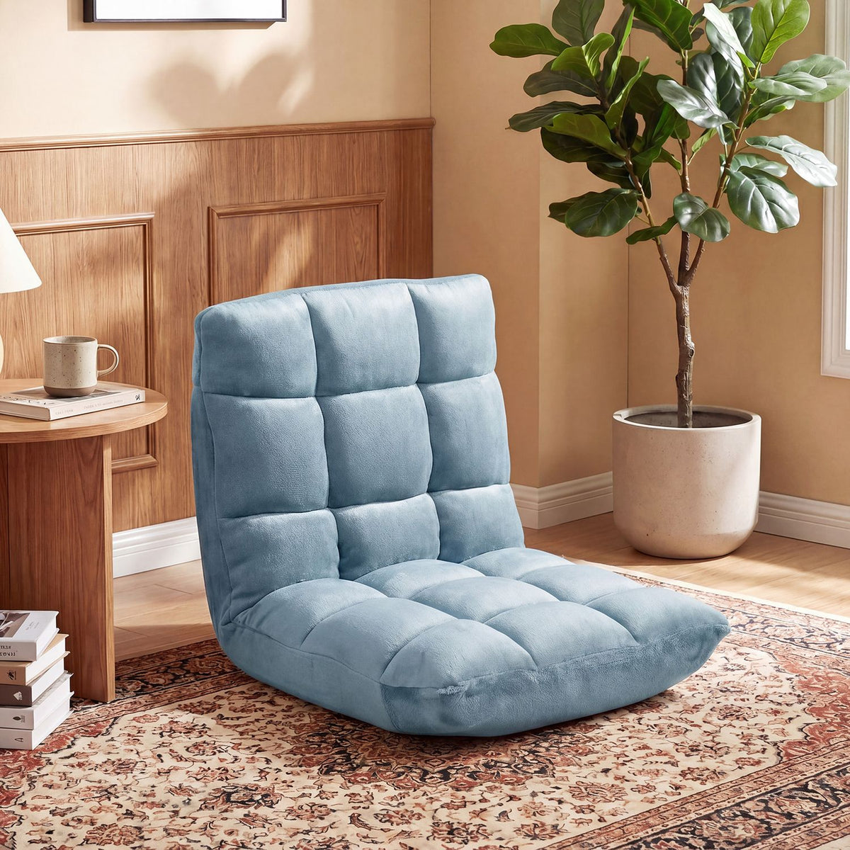 Blue tufted floor chair arranged on a patterned rug beside a wooden side table and potted plant.