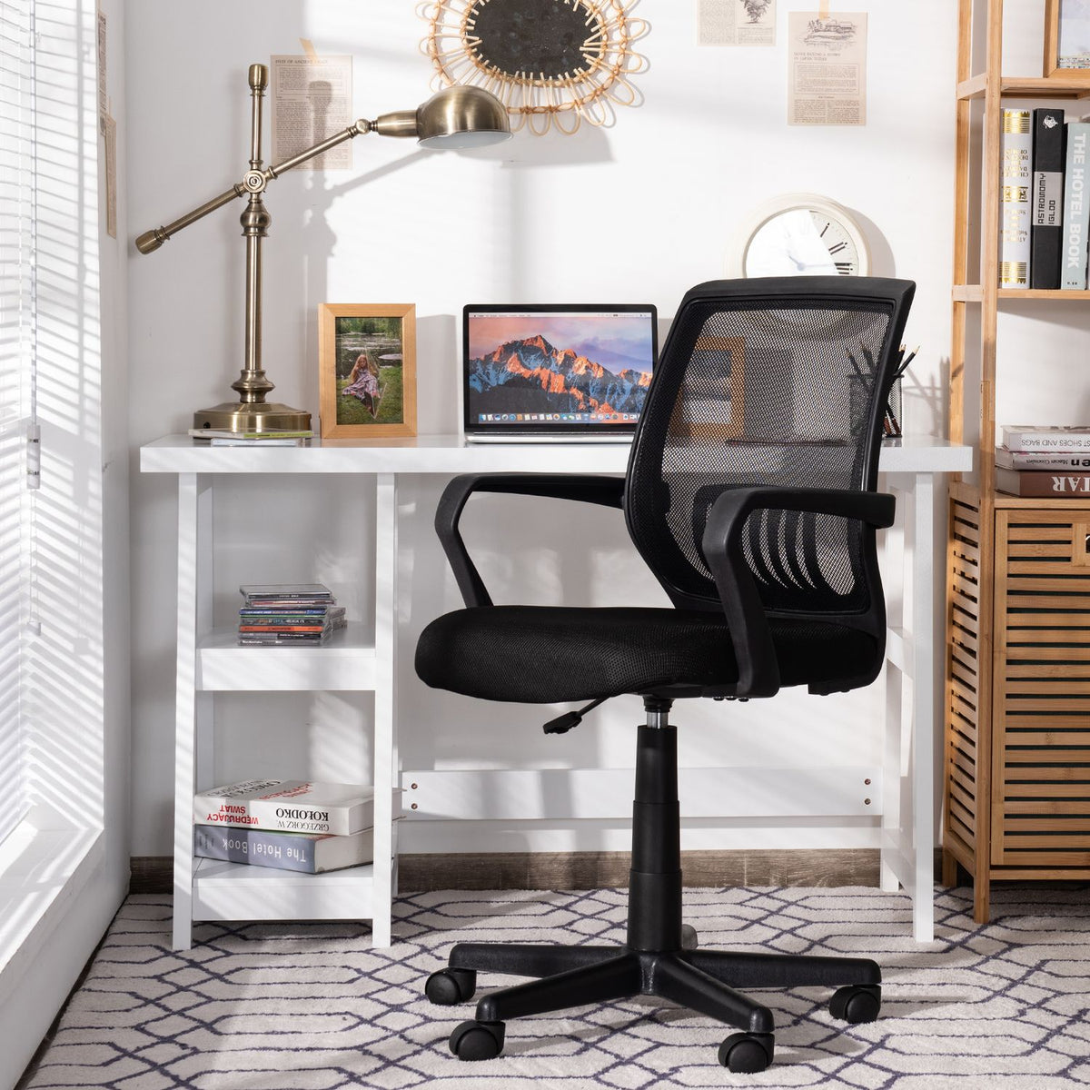 Black mesh office chair shown from behind at a desk, with its wheeled base visible.