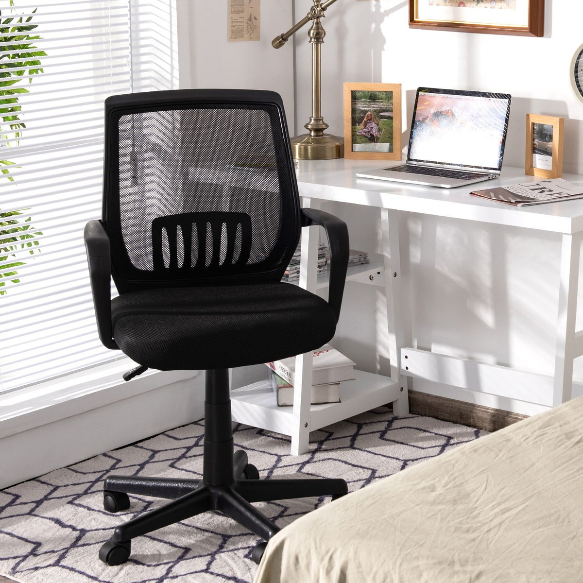 Black mesh office chair beside a white desk in a bright home office.