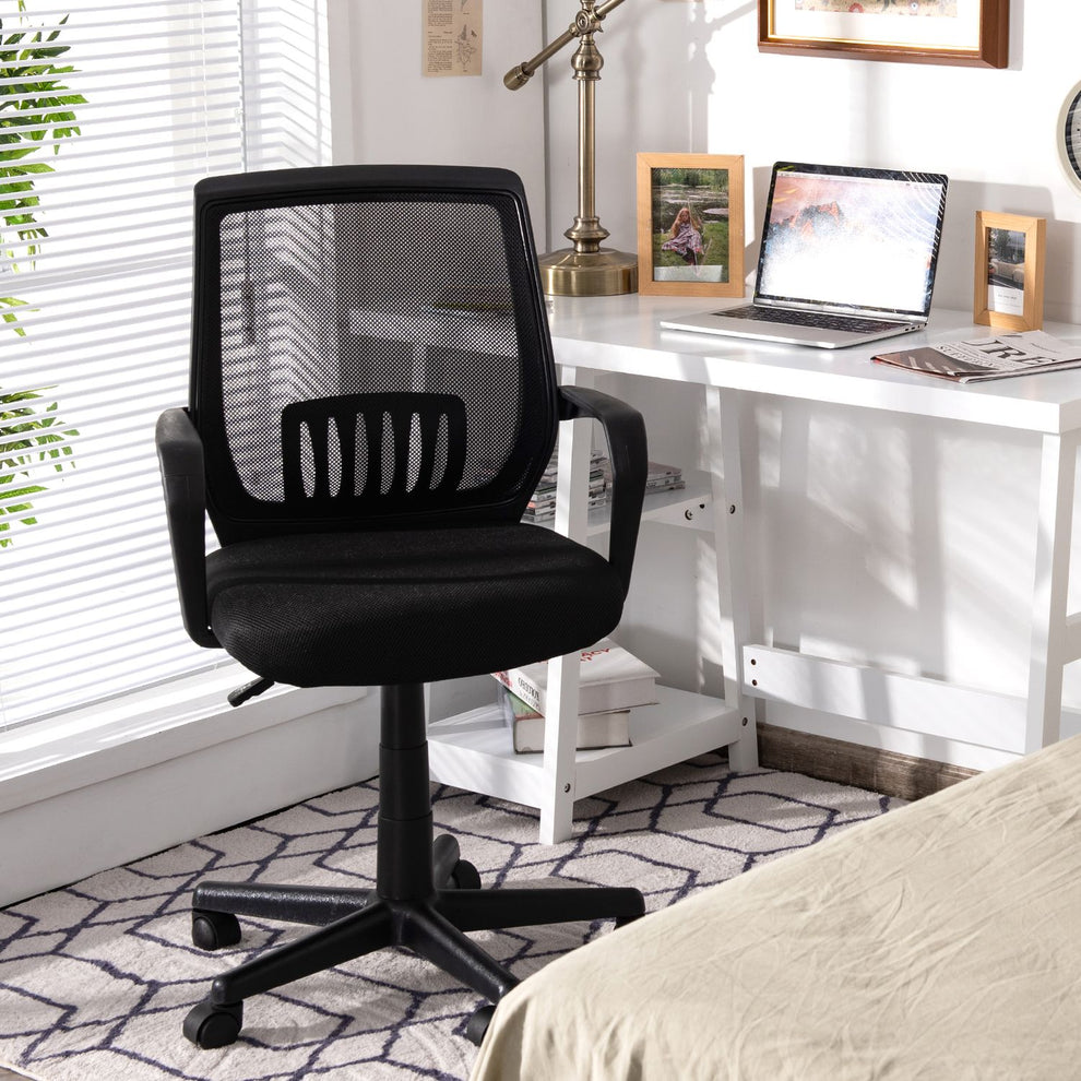 Black mesh office chair beside a white desk in a bright home office.
