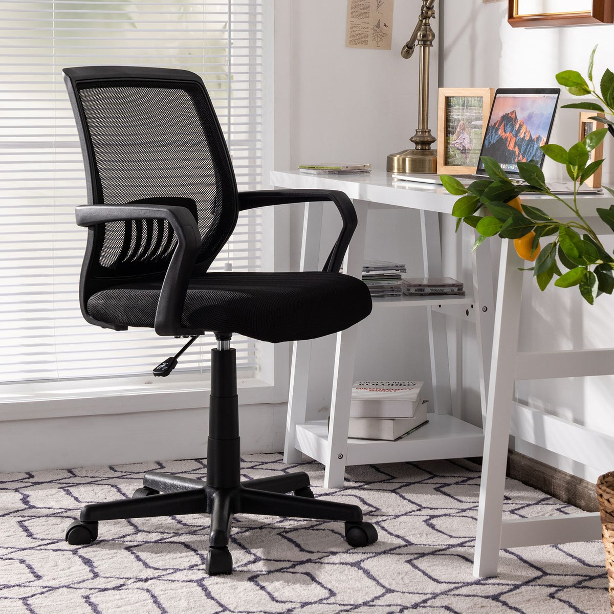 Black mesh office chair beside a white desk in a bright home office.