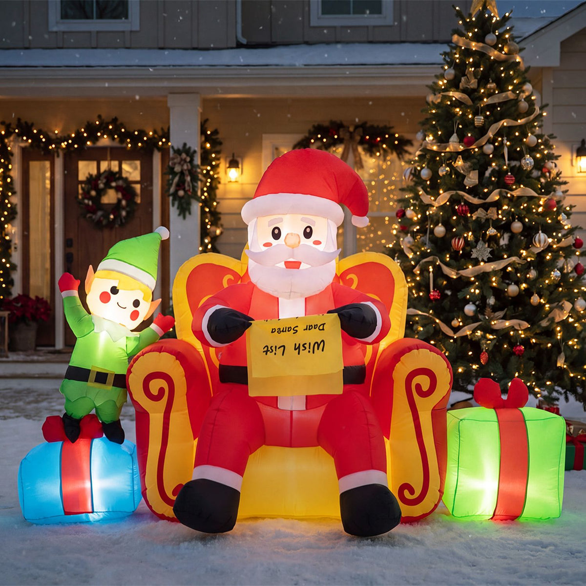 Front view of inflatable Santa and an elf seated beside bright gift boxes outside a decorated home.