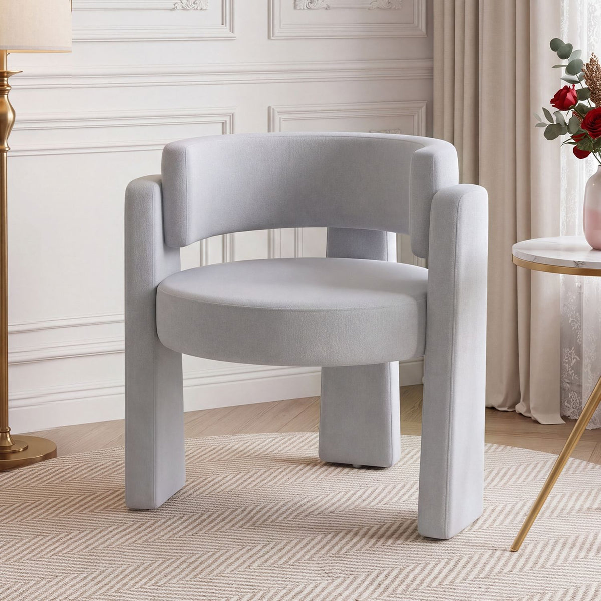 Light gray barrel chair with a curved back and open space beneath it, shown in a softly styled room.