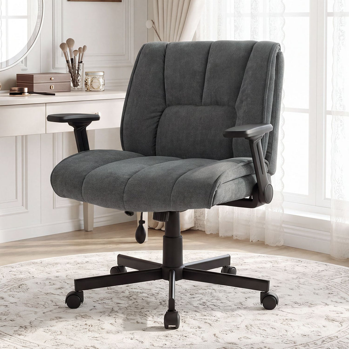 Charcoal office chair shown from the front at an angle against a bright window and white desk.
