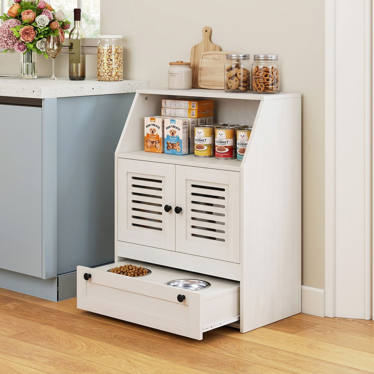 White feeding station beside a kitchen counter, with food stored on its shelf and one bowl of kibble in the open drawer.