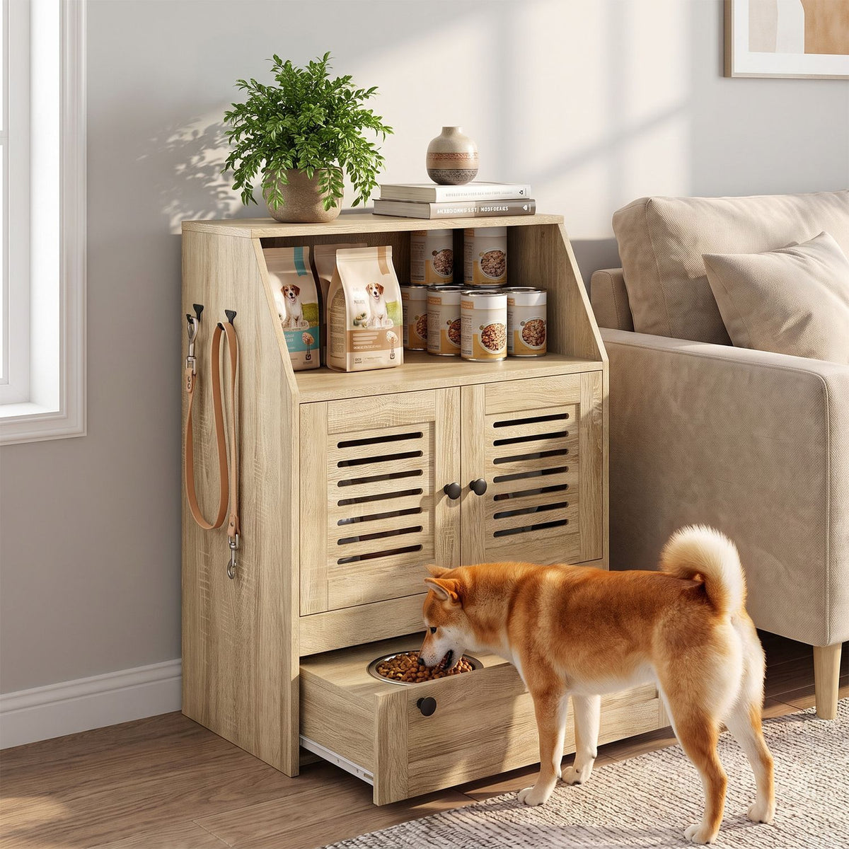 A tan dog eats from a pull-out feeding drawer in a light wood storage cabinet beside a sofa.