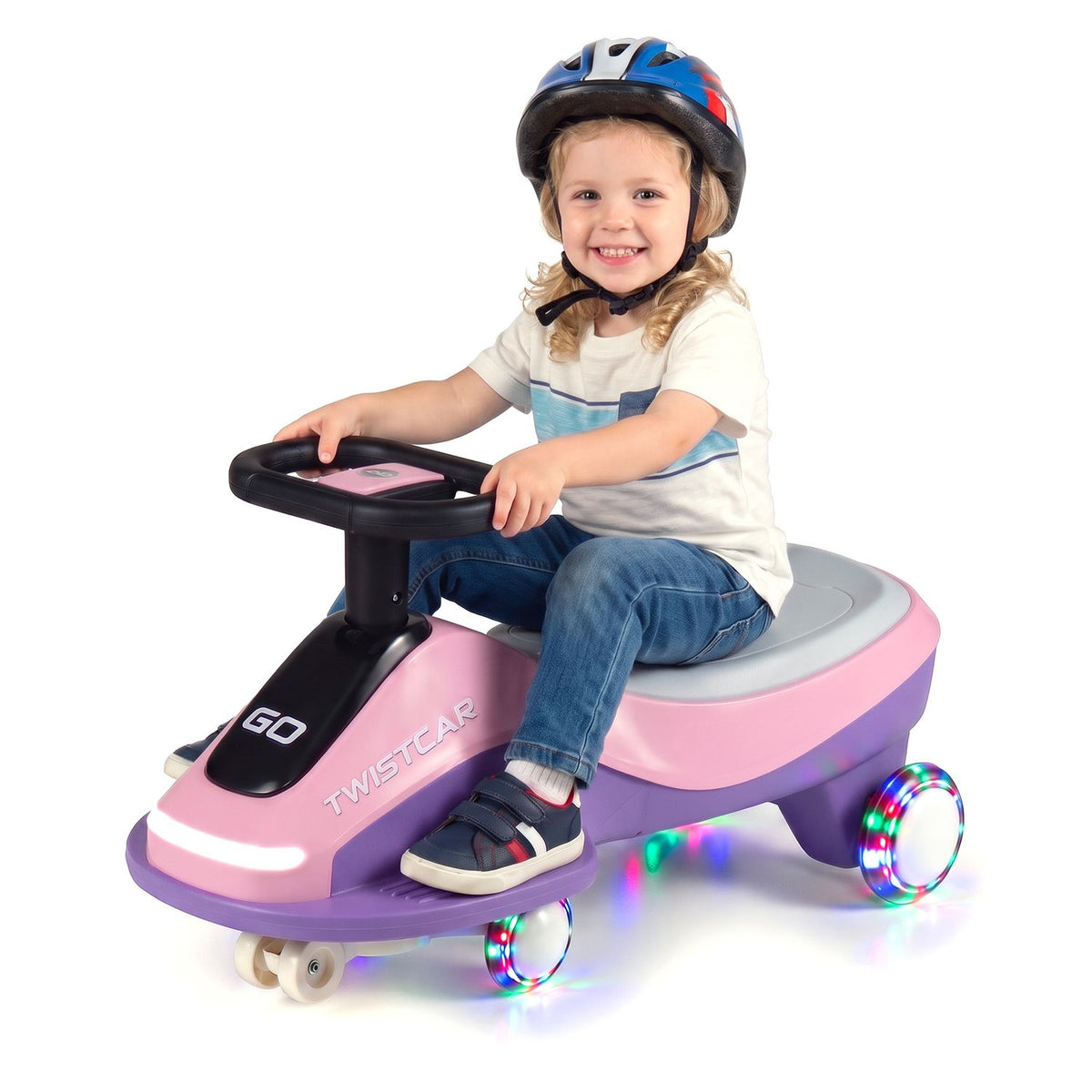 A helmeted child sits on the pink-and-purple ride-on car against a white background.