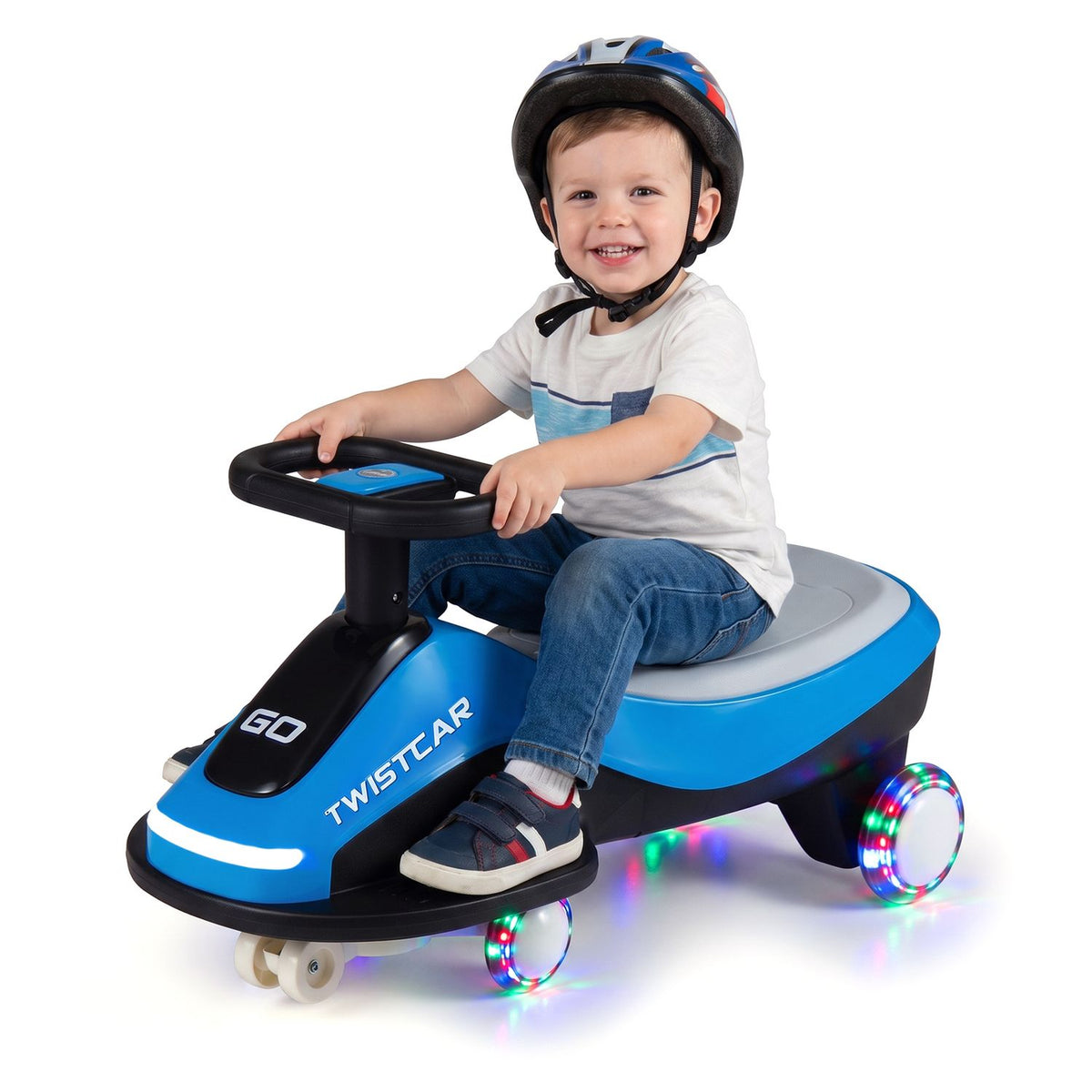 A helmeted child sits at the steering wheel of the blue ride-on car against a white background.
