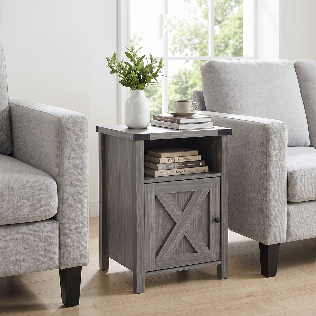 Gray farmhouse nightstand between two light upholstered chairs, with books and a vase on top.