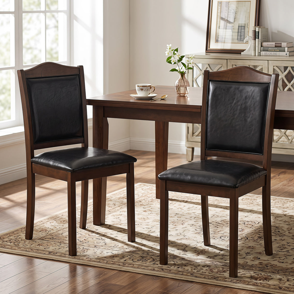 Two dark upholstered wooden dining chairs beside a dining table in a bright room.