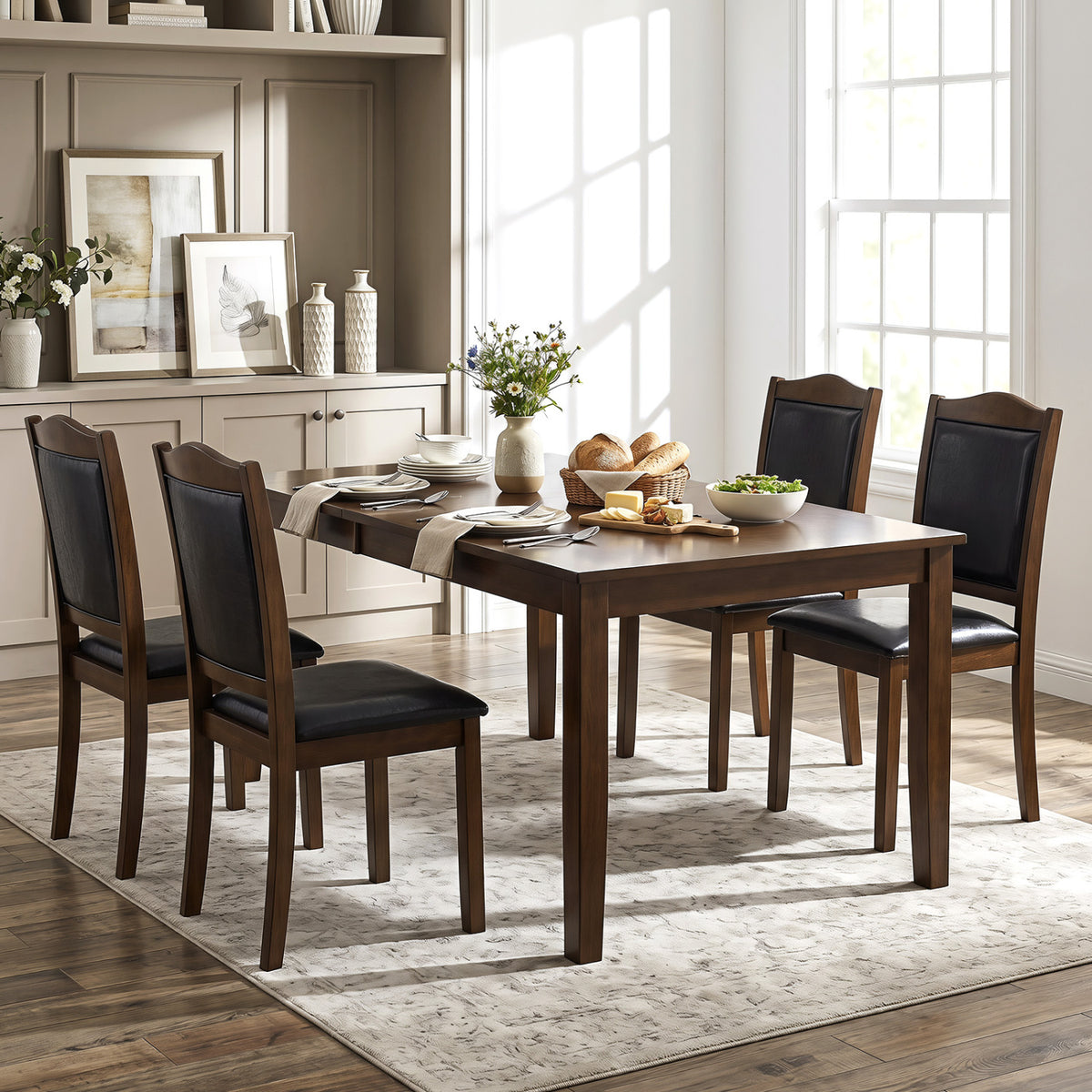 Four dark upholstered chairs arranged around a rectangular dining table in a bright room.