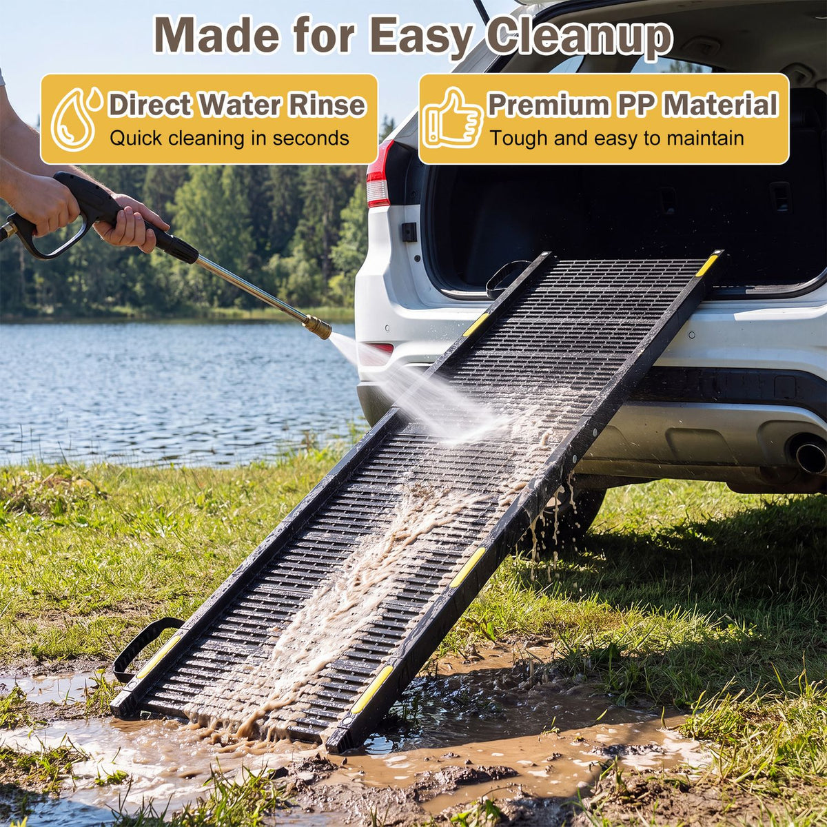 A person sprays water over the ramp as it rests against an SUV, washing mud from its surface.