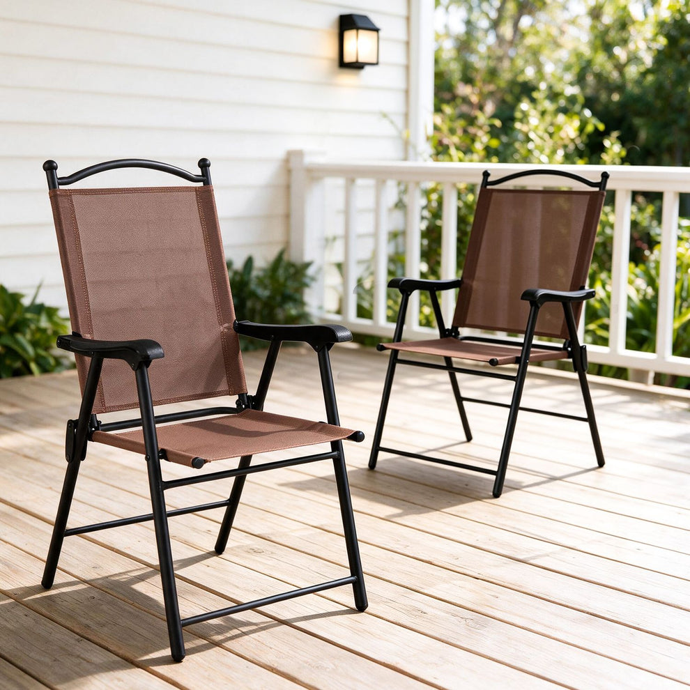 Two brown fabric folding chairs sit on a sunlit wooden deck beside a white railing.