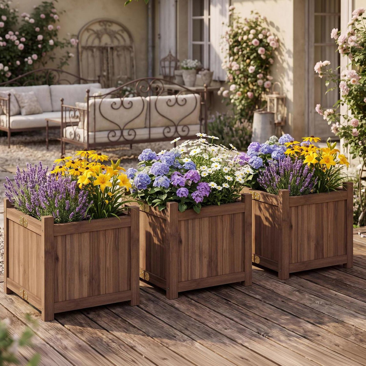 Three wooden square planters filled with colorful flowers sit on a garden patio.