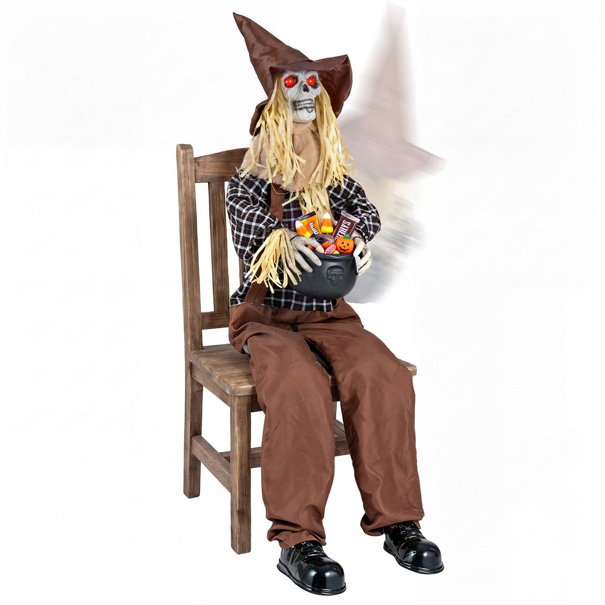 Sitting scarecrow with candy bowl displayed on a wooden chair against a white background