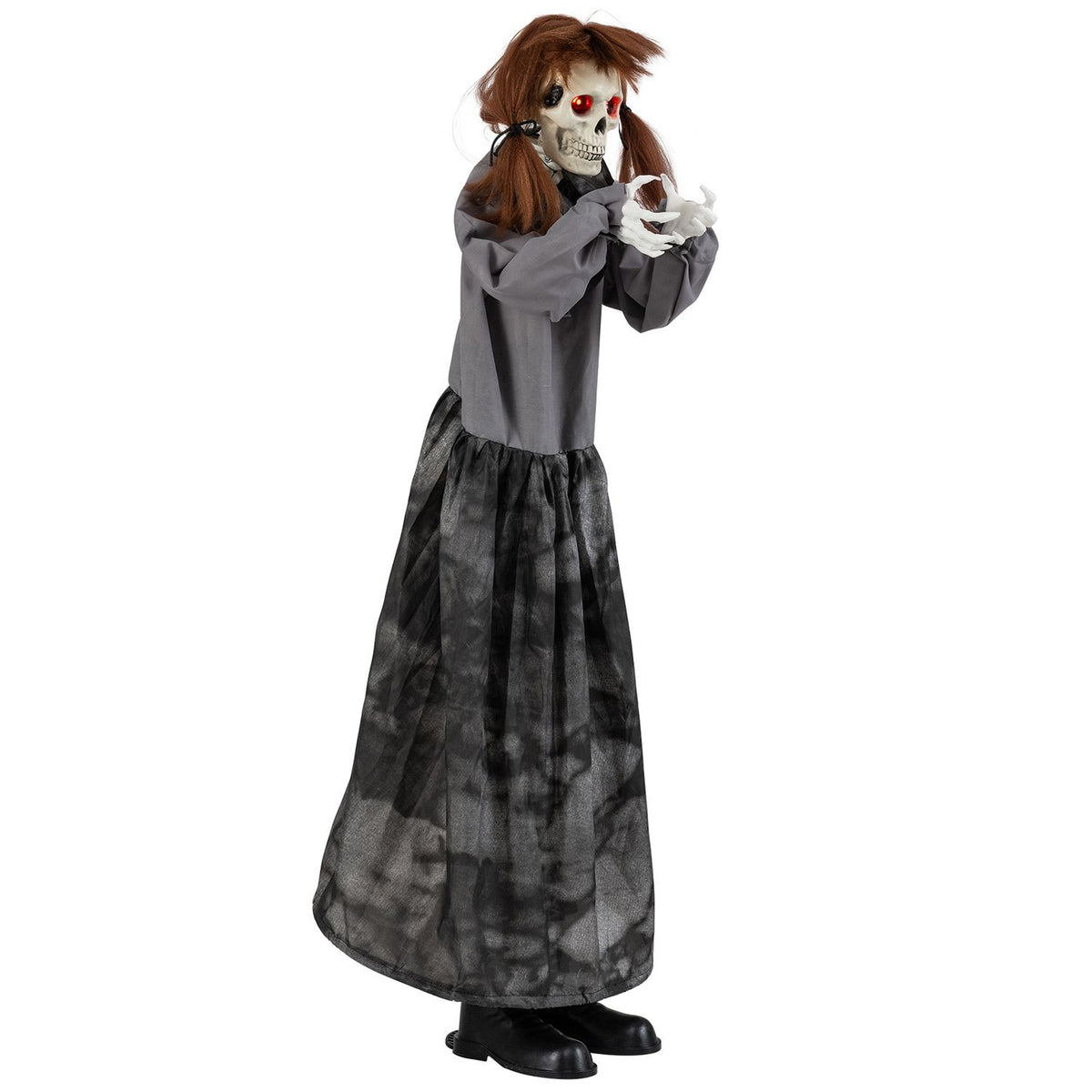 The skeleton doll shown from the side with its hands raised, wearing a gray top and long dark skirt.