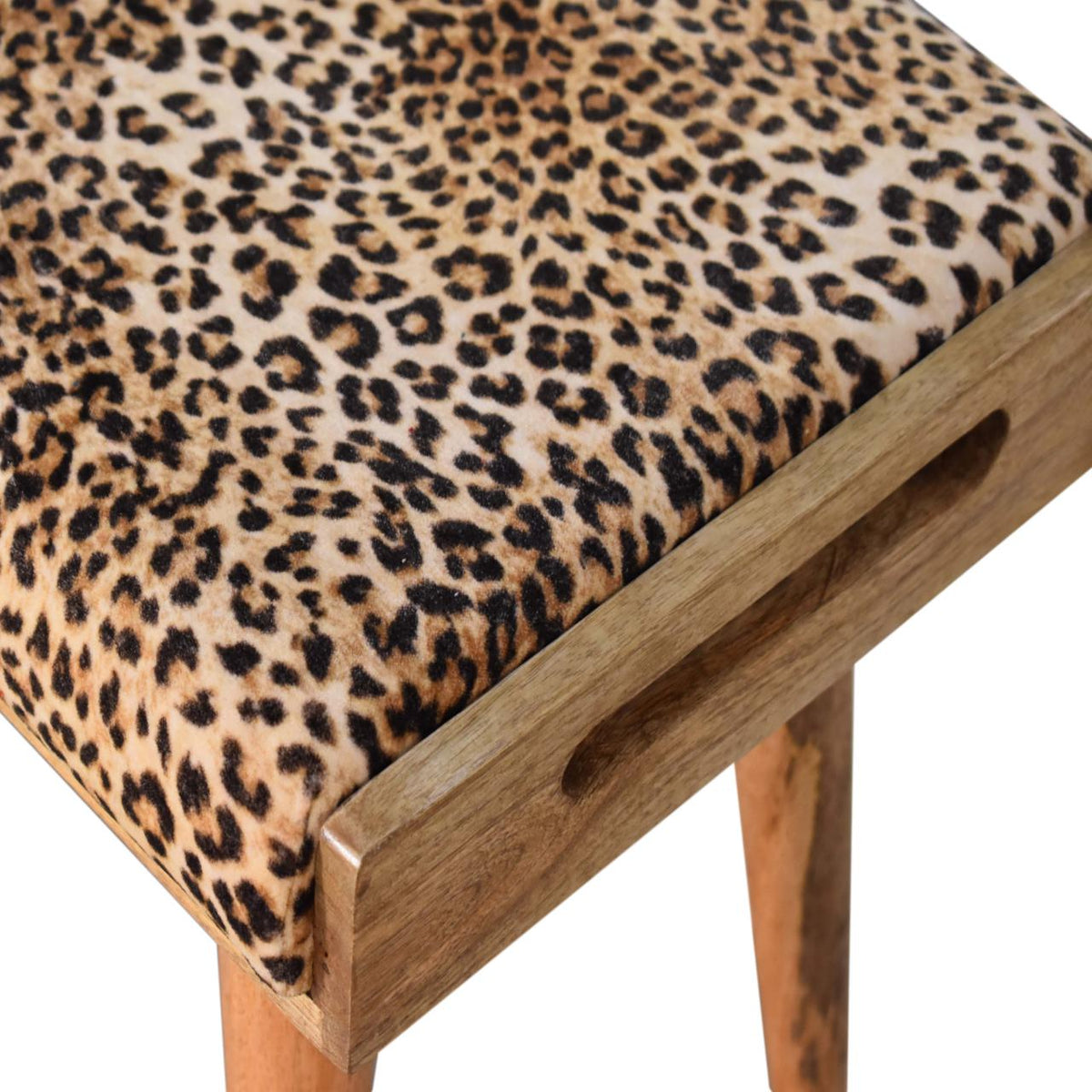 Angled close-up of leopard-print upholstery, wood tray edge, and an inset side opening