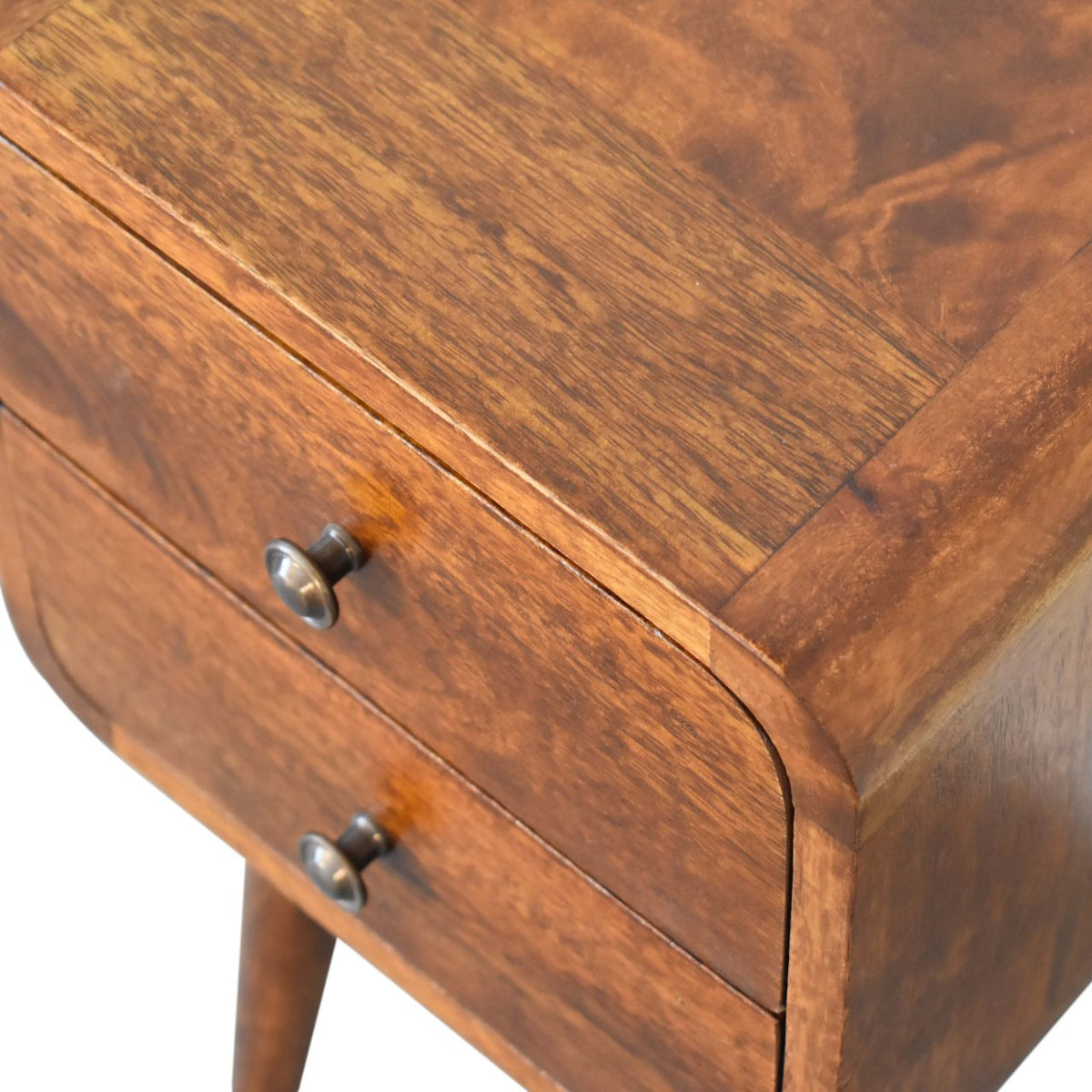 Overhead close-up of the chestnut wood top, curved corner and drawer knobs
