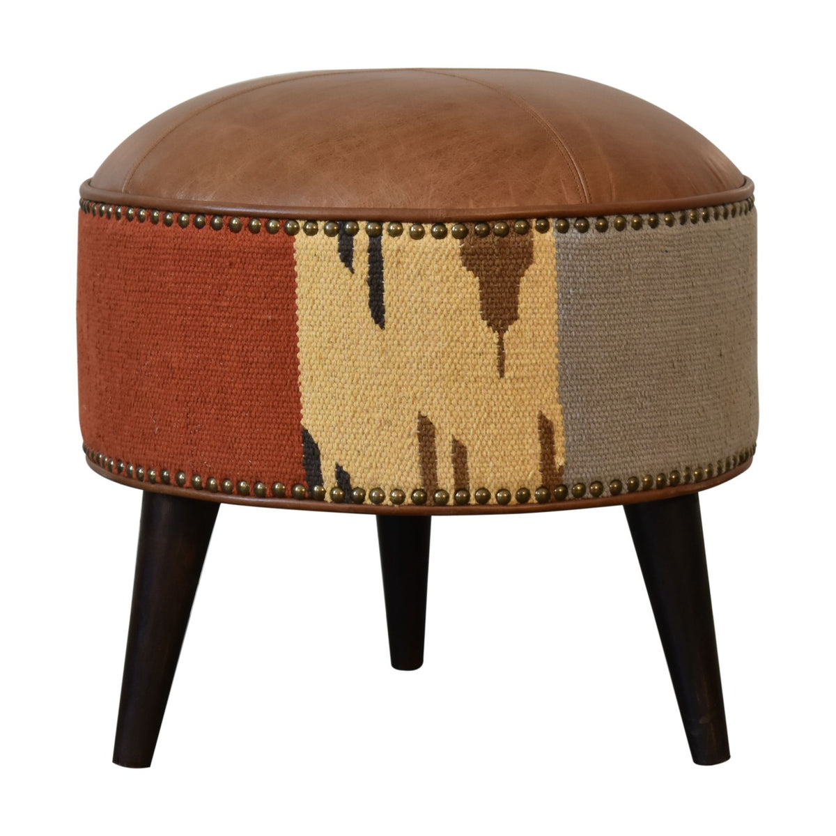 Front view of a round tan and rust footstool with patterned sides and dark tapered legs.