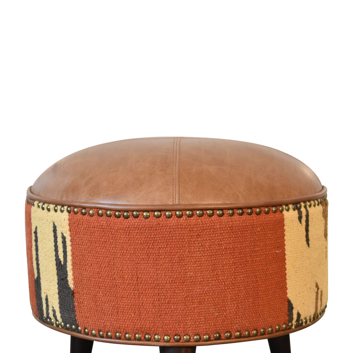Close view of the footstool's rust-and-cream patterned side and rounded tan leather top.