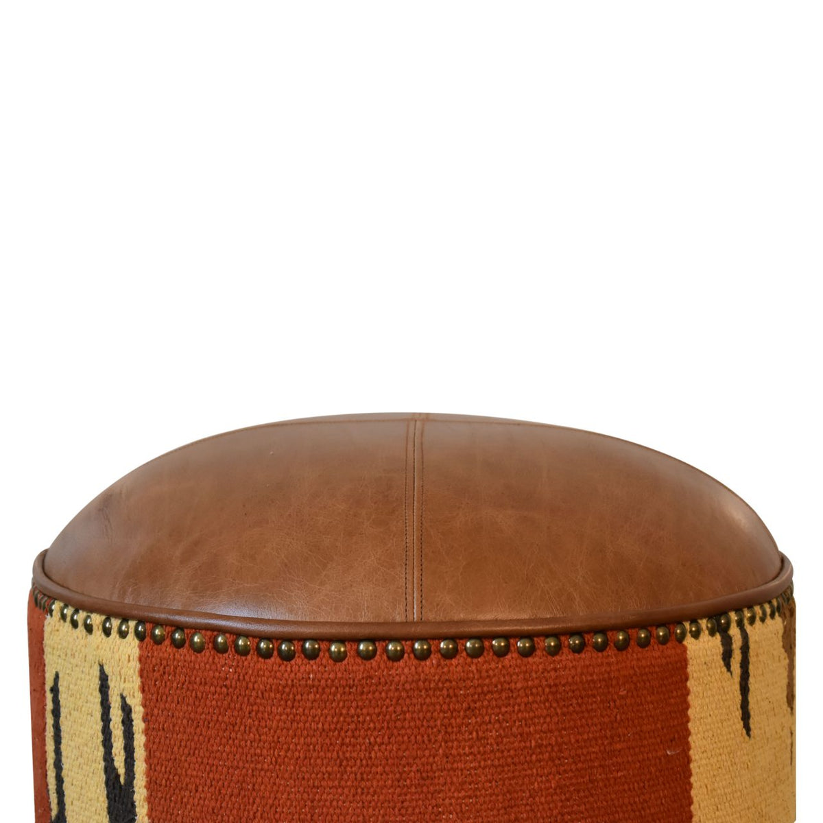 Tight view of the tan leather top above the rust and cream patterned fabric side.