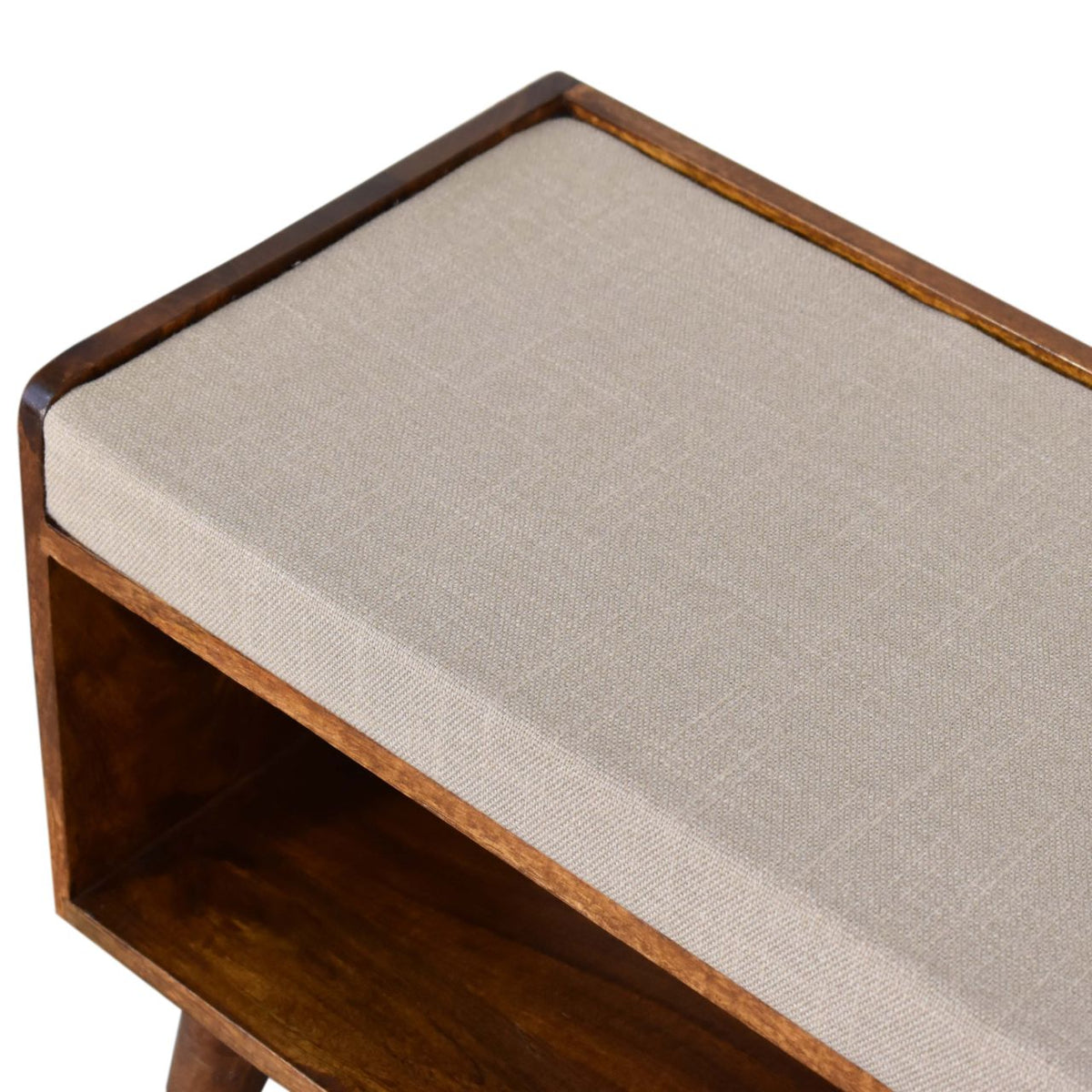 Angled top view of the beige upholstered seat and open shelf on a chestnut bench