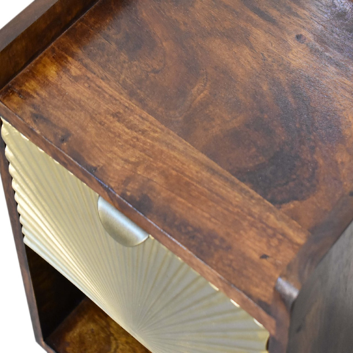Overhead angled close-up of the chestnut tabletop and gold drawer front