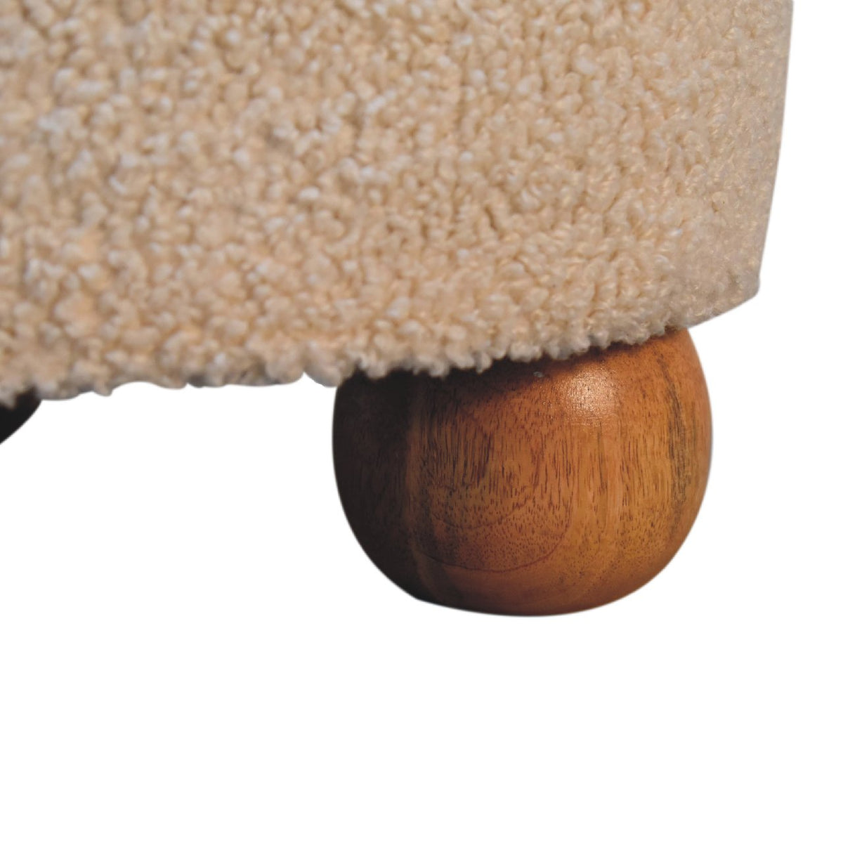 Close-up of a rounded wooden foot beneath the cream boucle body