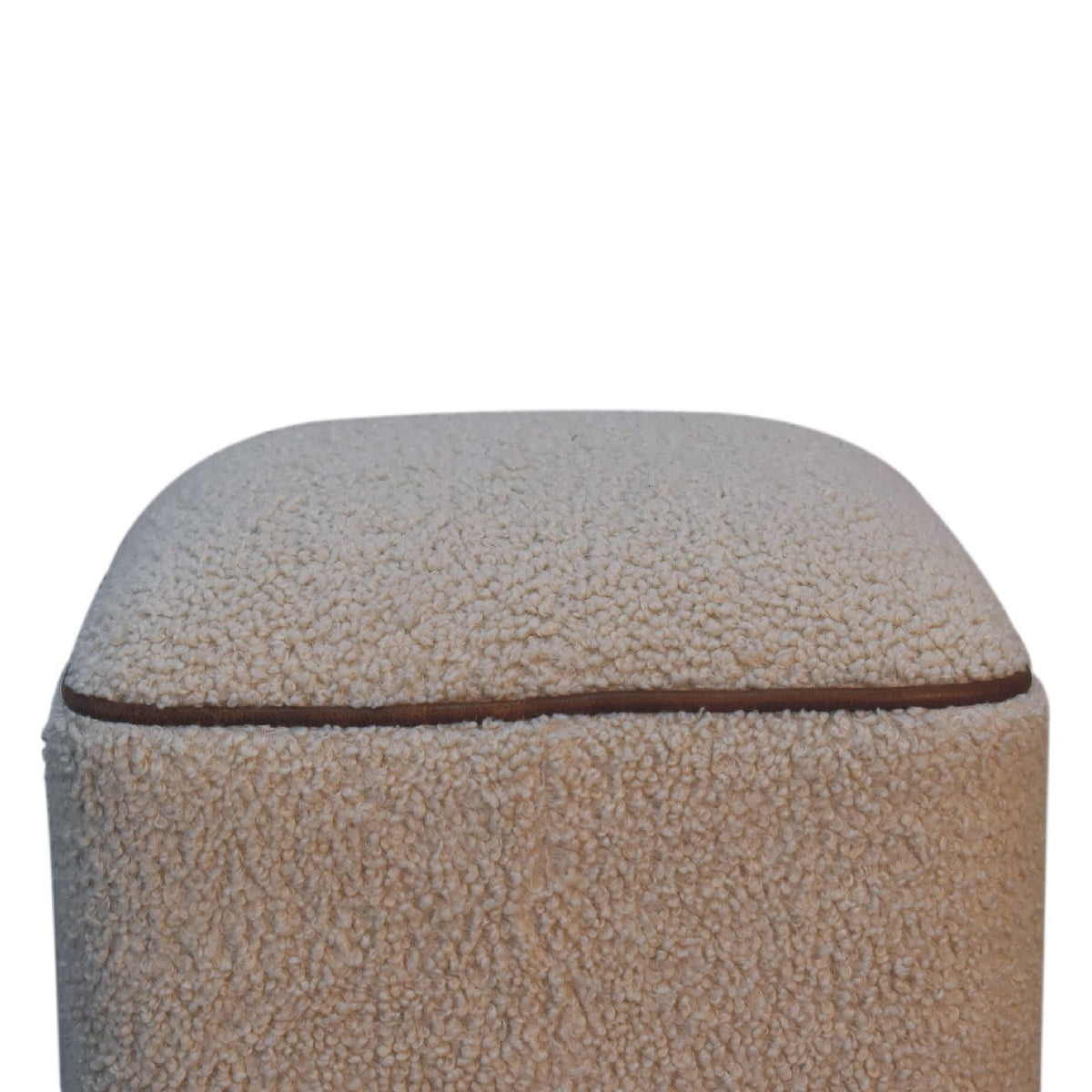 Close-up of textured beige upholstery and brown piping along the footstool rim