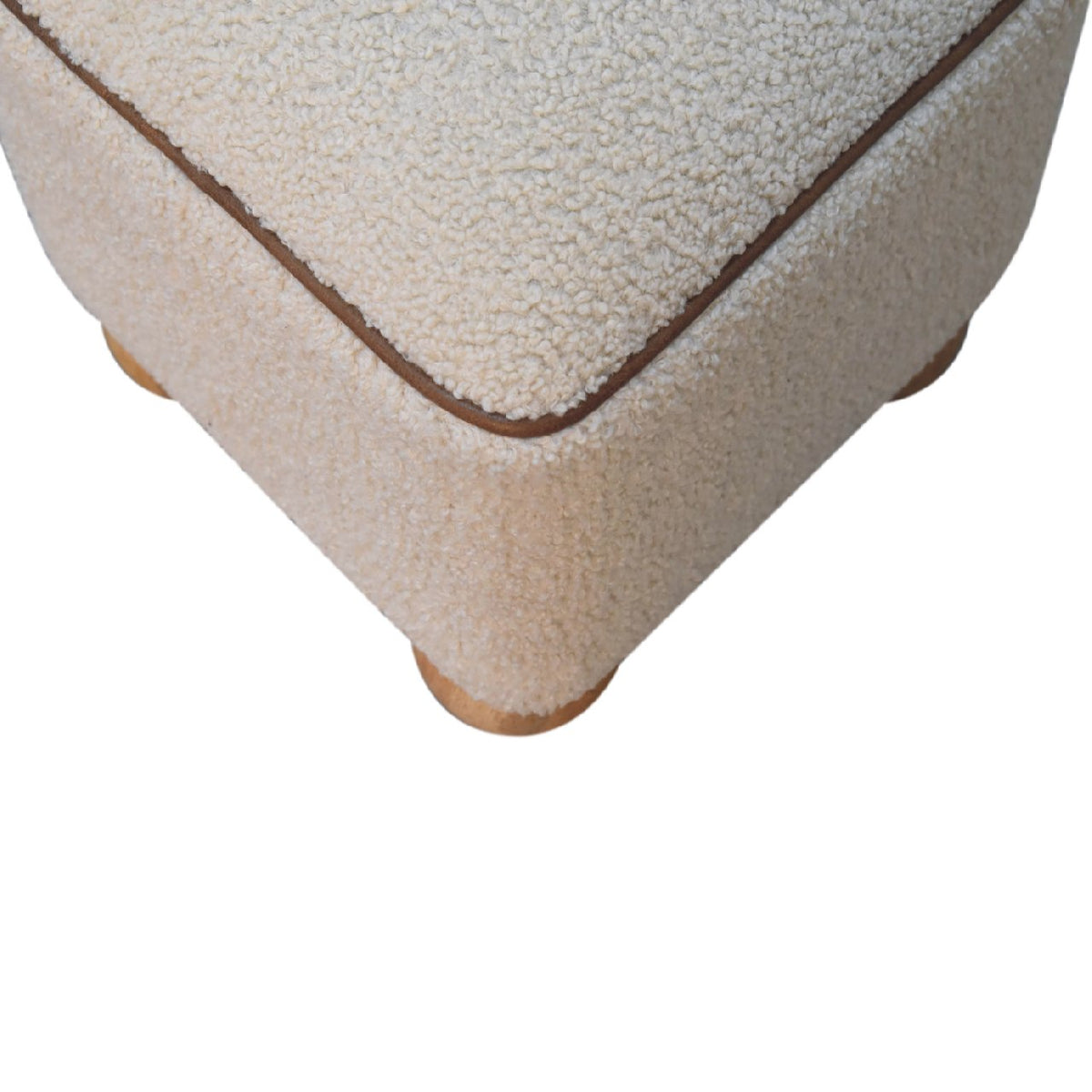 Top-down angled detail of the beige footstool and its brown rim piping