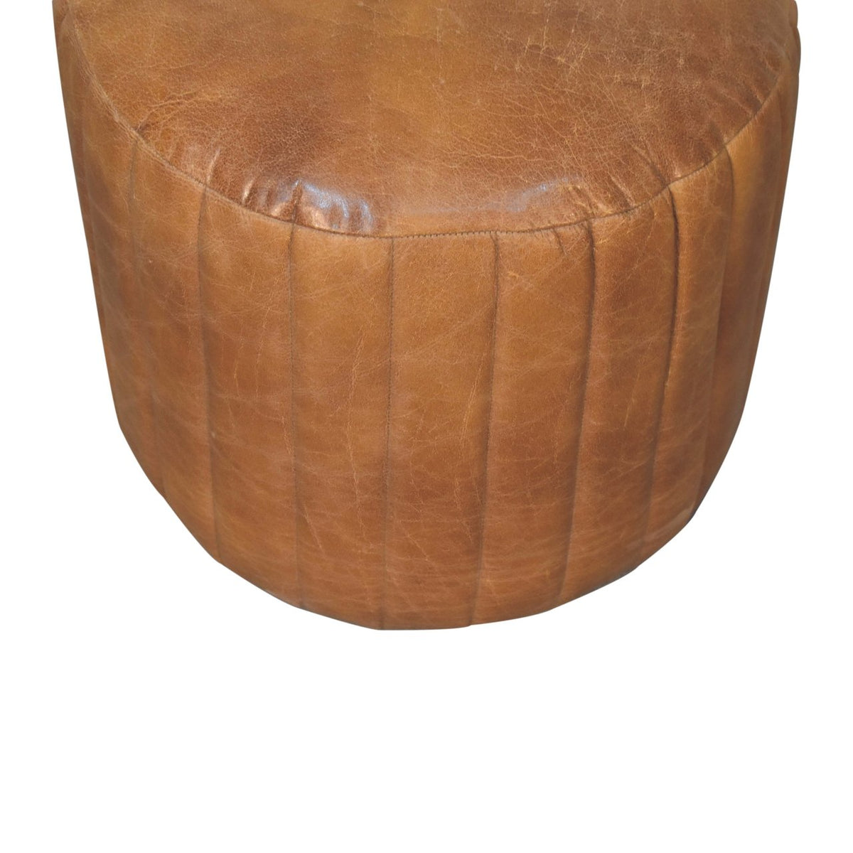 Close angled view of the brown footstool top and stitched sides