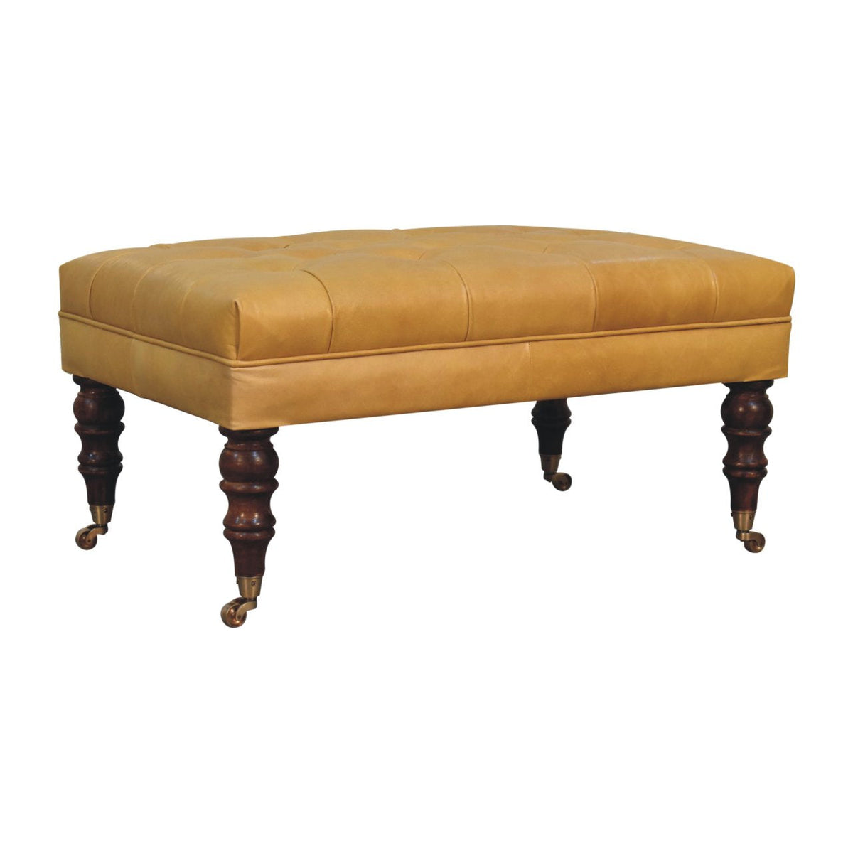 Opposite corner view of the tan ottoman, with stitched upholstery and dark carved legs on casters.