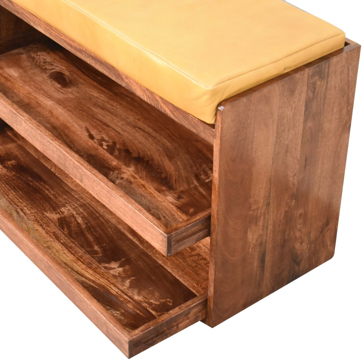 Close view of a tan cushioned bench top above two open wooden shoe shelves.