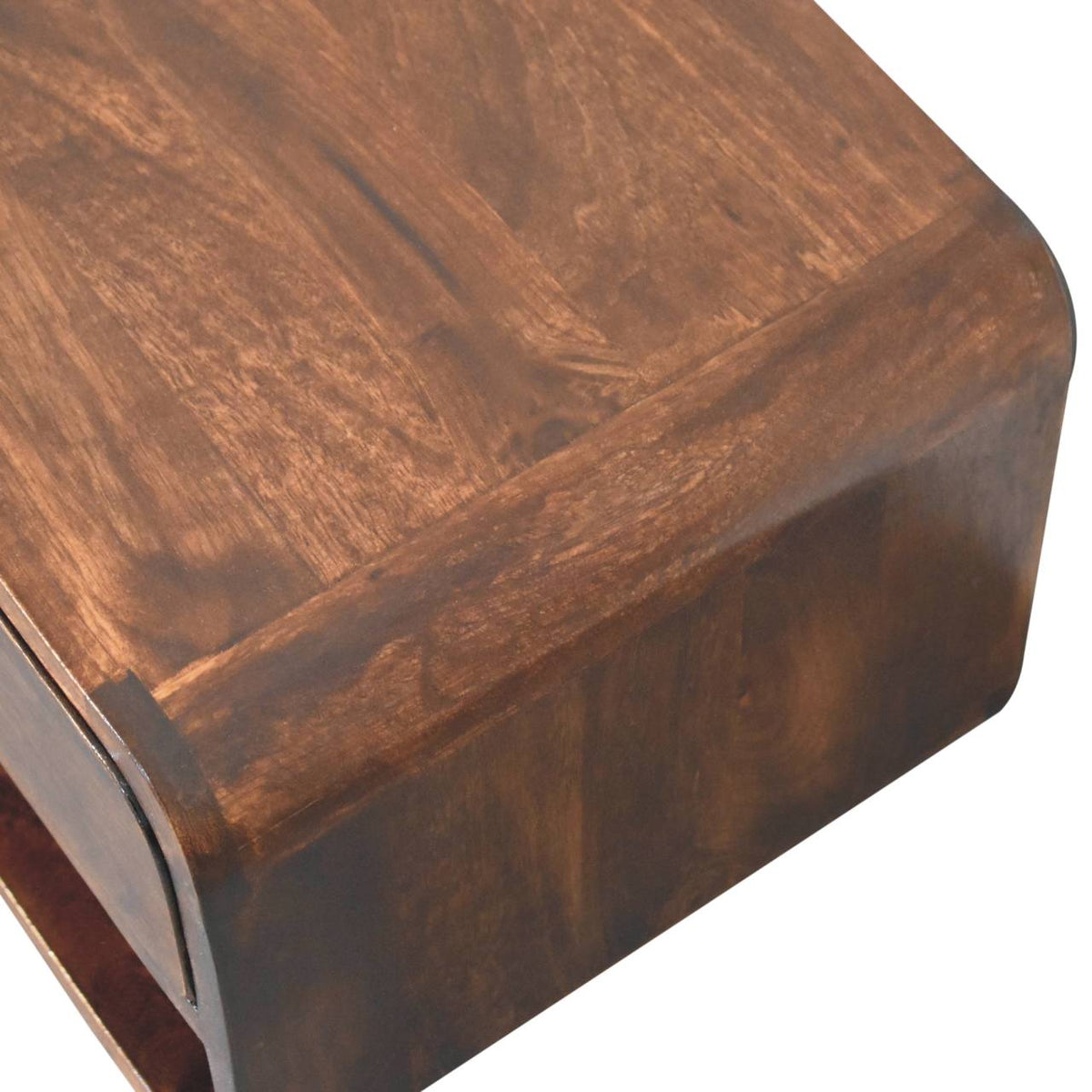 Close-up of a rounded bedside table corner with a richly patterned brown wood surface.