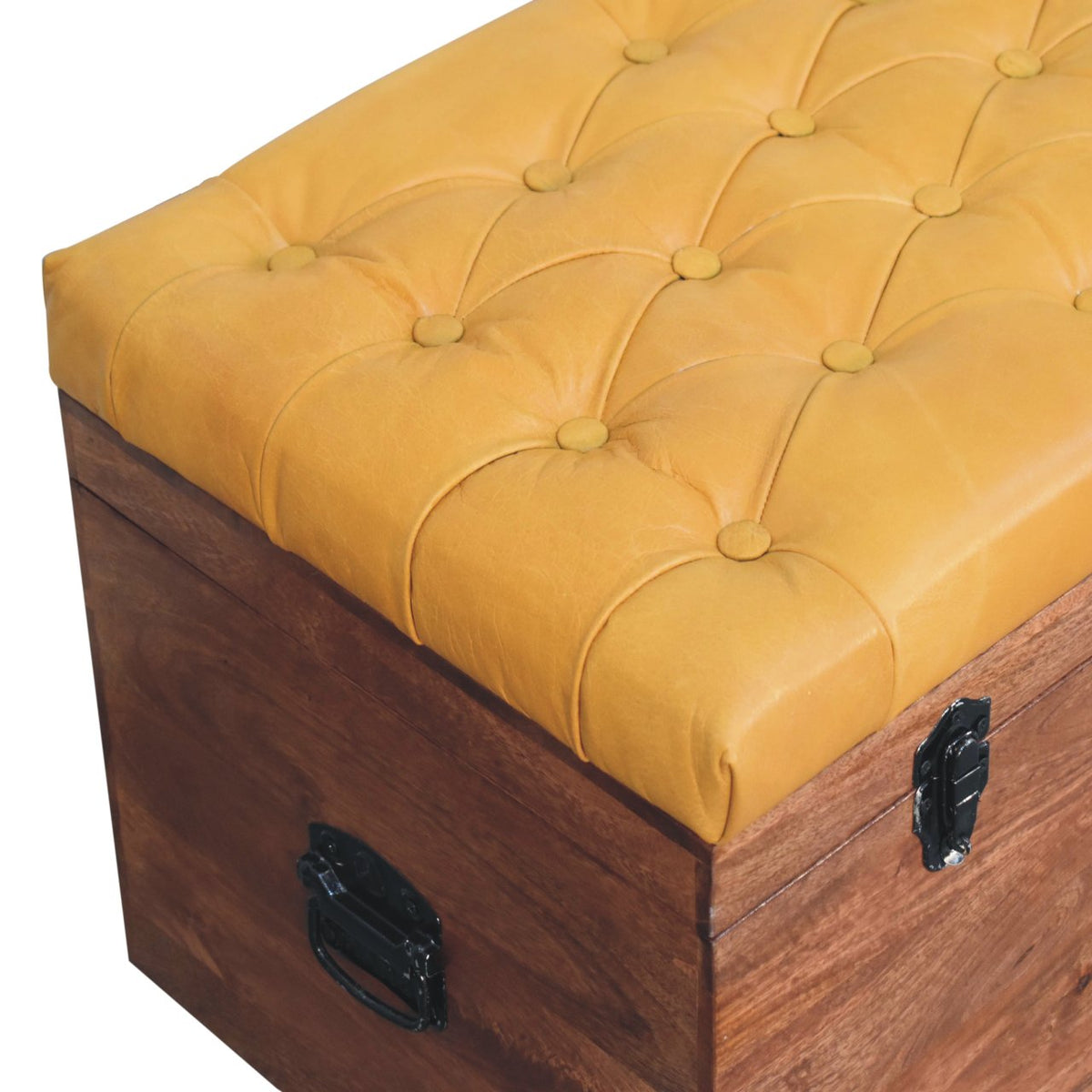 Angled overhead view of the button-tufted golden upholstery and wooden trunk side.