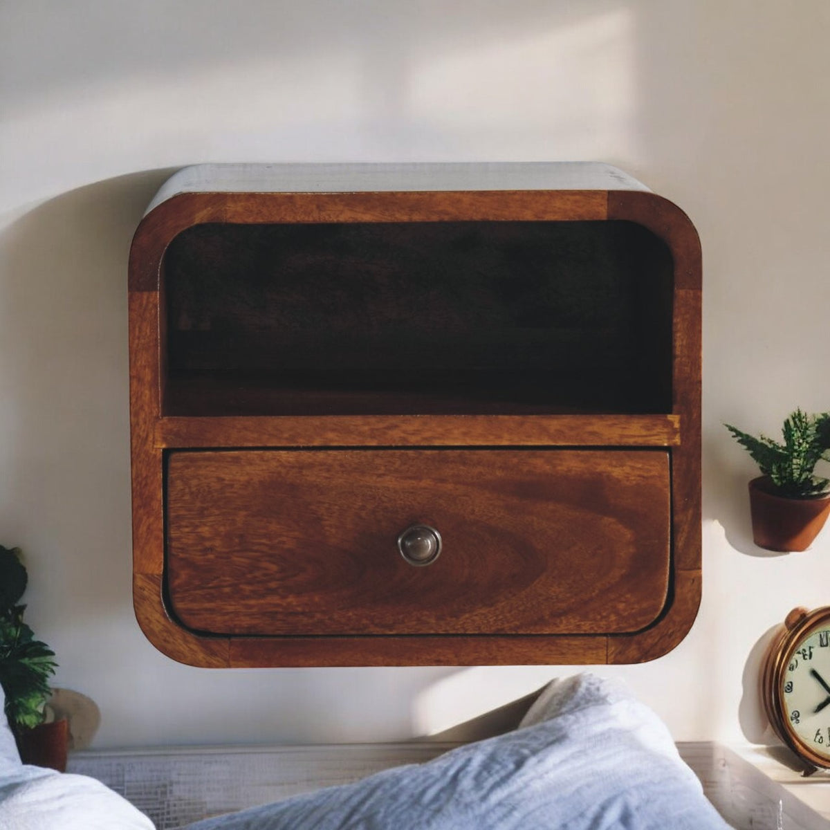 Curved wooden bedside cabinet mounted above a bed, with an open slot and a drawer.