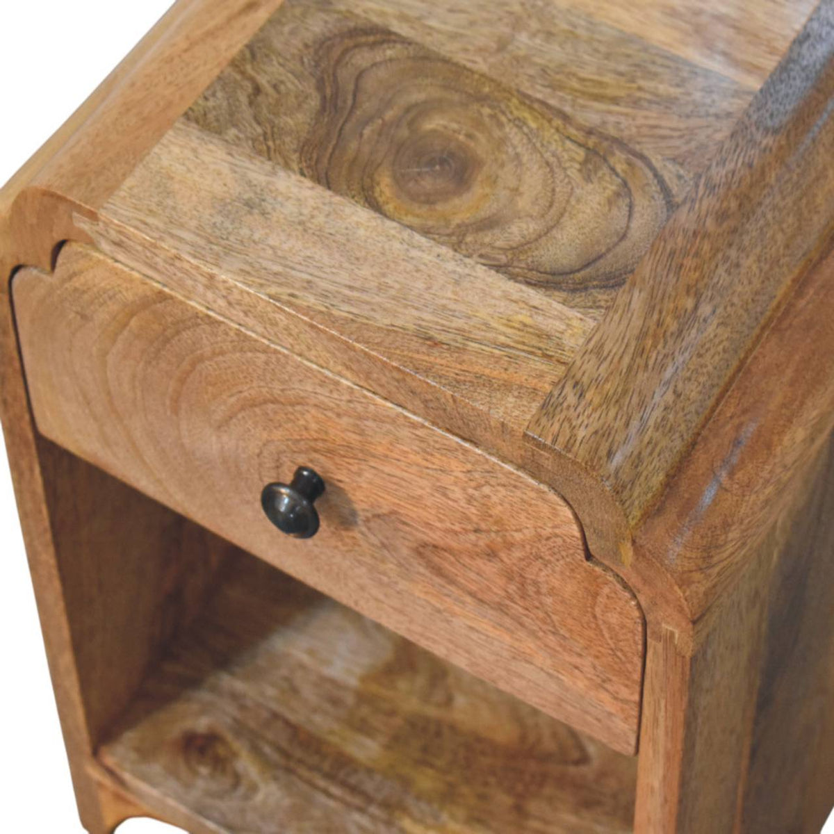 Close-up of the nightstand’s closed drawer, black knob, open shelf and richly grained wood top.