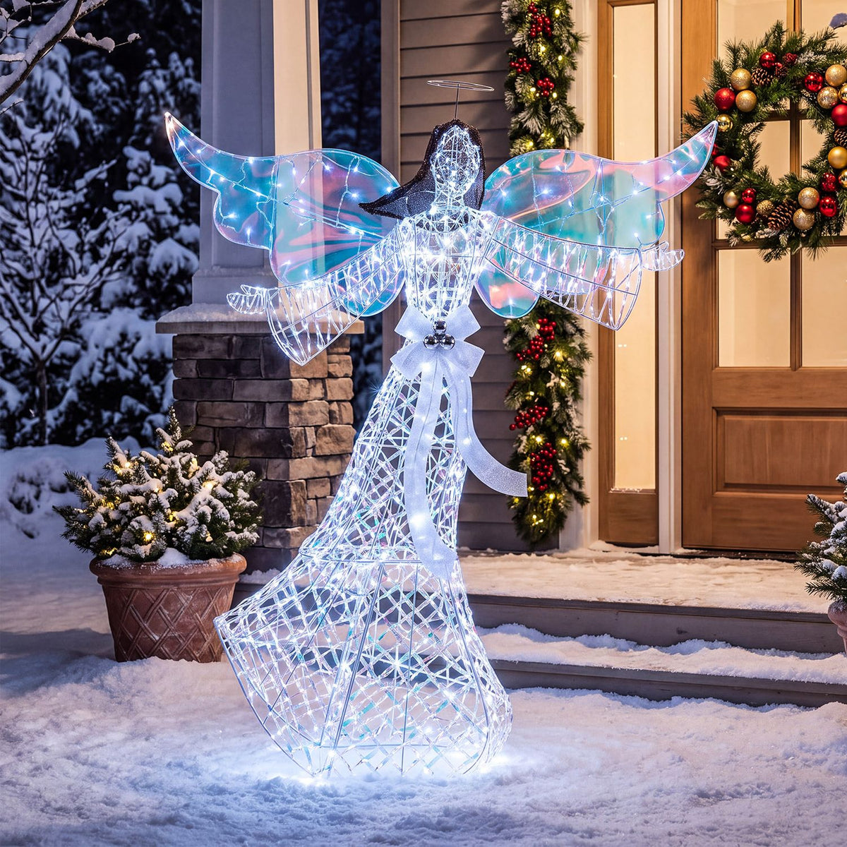 A luminous angel decoration stands in the snow before a decorated front door and wreaths.