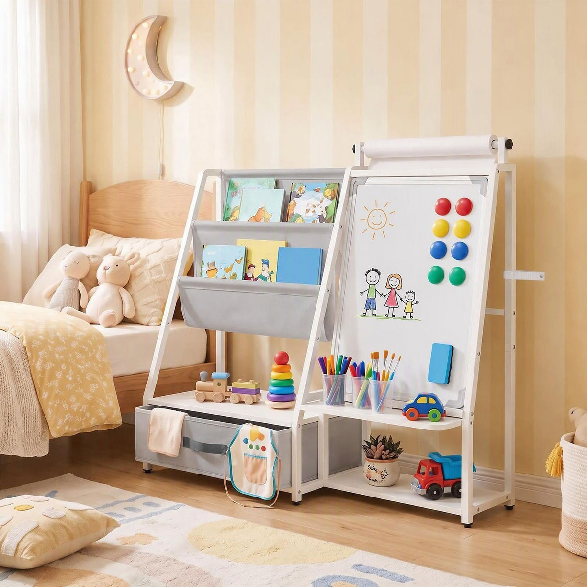 The gray bookshelf easel stands beside a bed, with books, art supplies, toys, and drawings on its board.