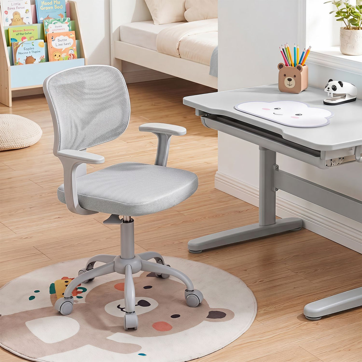 Gray mesh-back chair with armrests beside a white desk in a bright bedroom