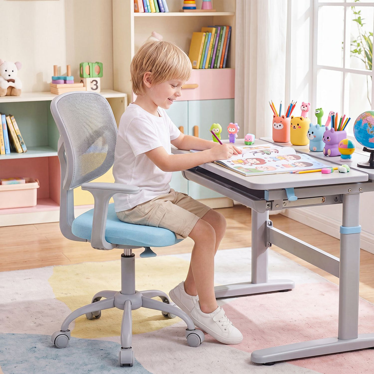 A child sits in a light blue and gray swivel chair at a desk, drawing in a bright playroom.