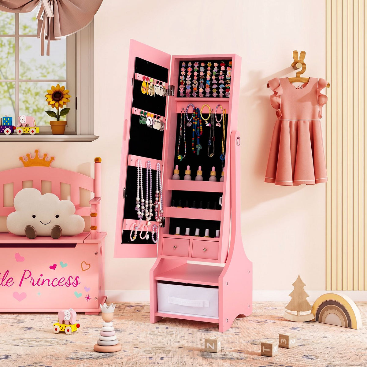 Open pink jewelry armoire displaying jewelry inside, beside a bed and a hanging dress.