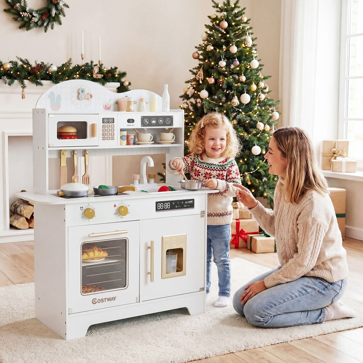 A child plays at a white toy kitchen while an adult kneels beside her in a decorated living room.