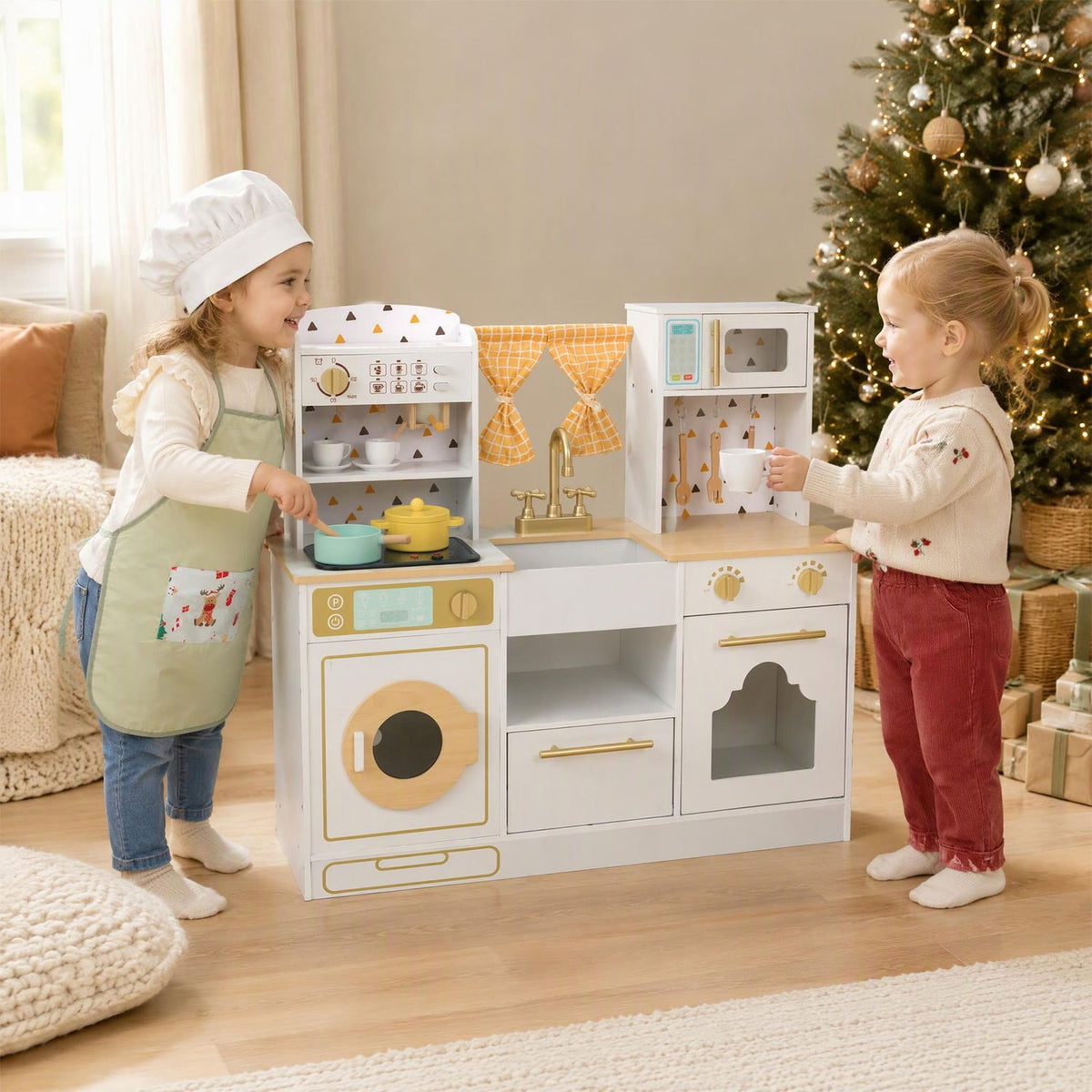 Two children play at a toy kitchen with orange curtains, a sink, shelves, and toy cookware.