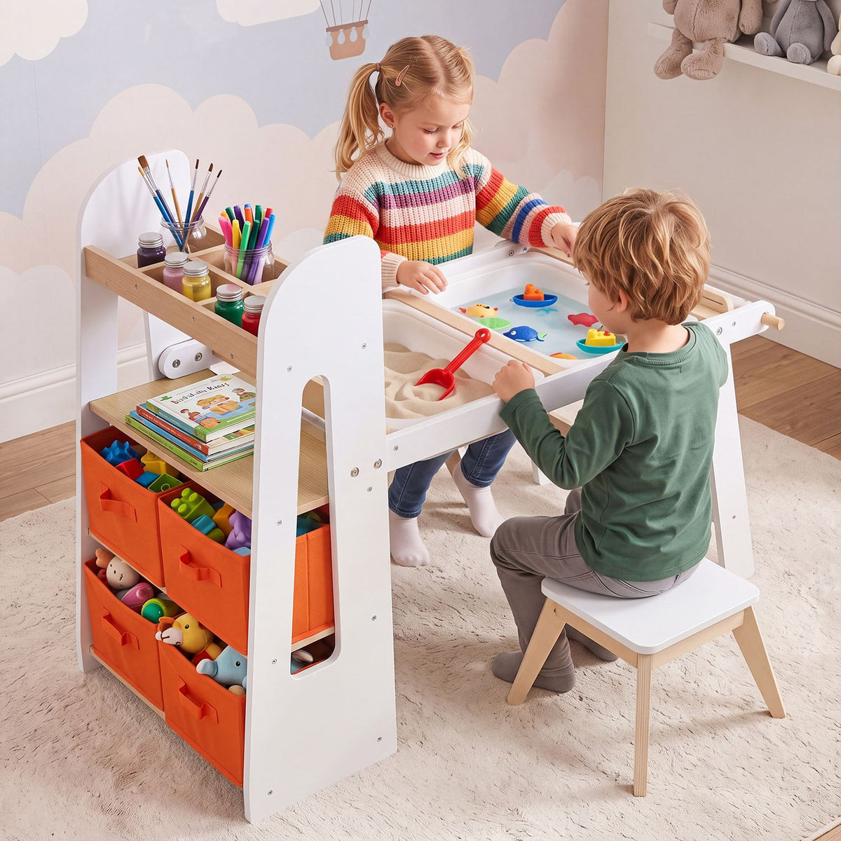 Two children use a white art table with colorful supplies, orange storage bins, and a stool.