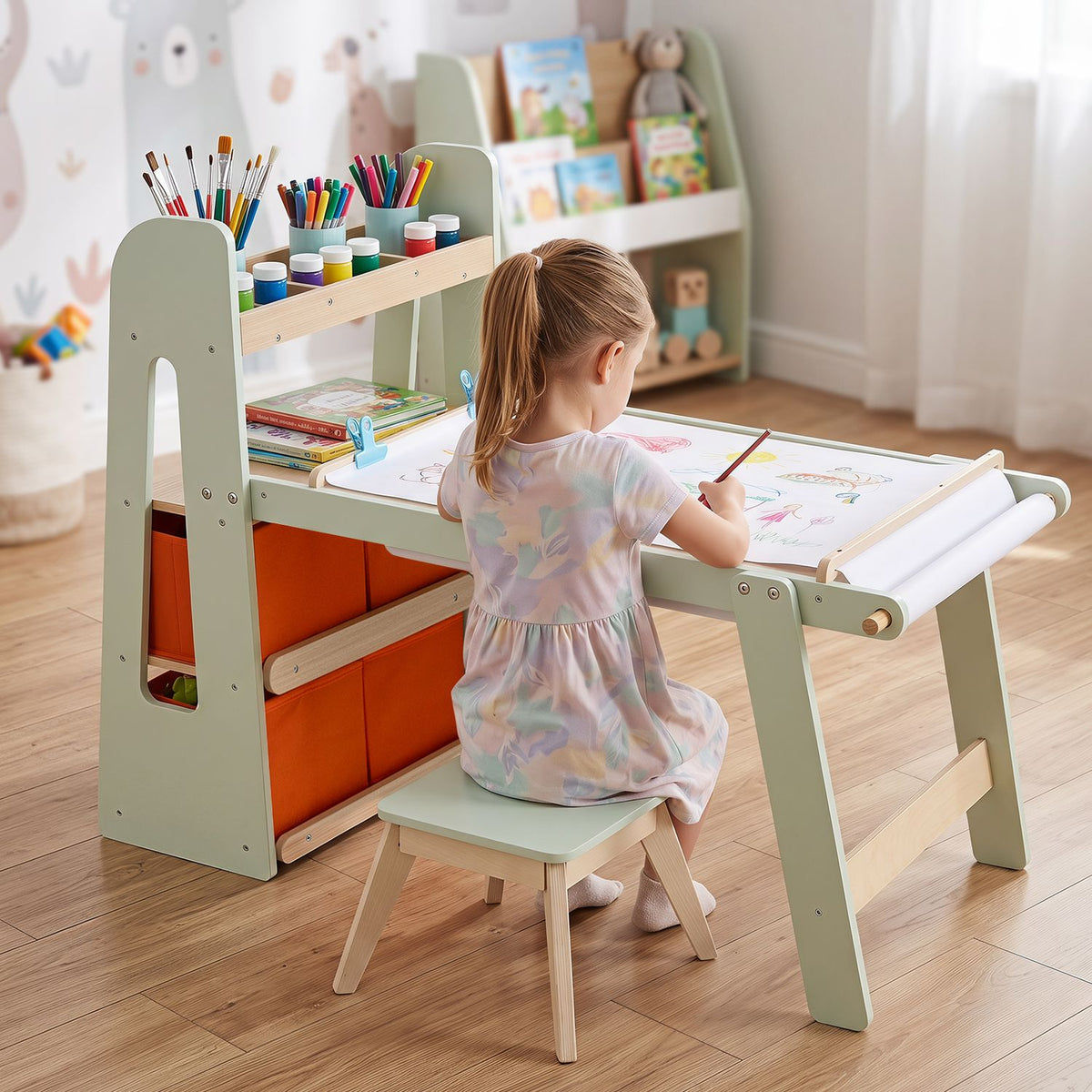 A child paints at the table as paper unrolls across its surface, with art supplies stored nearby.