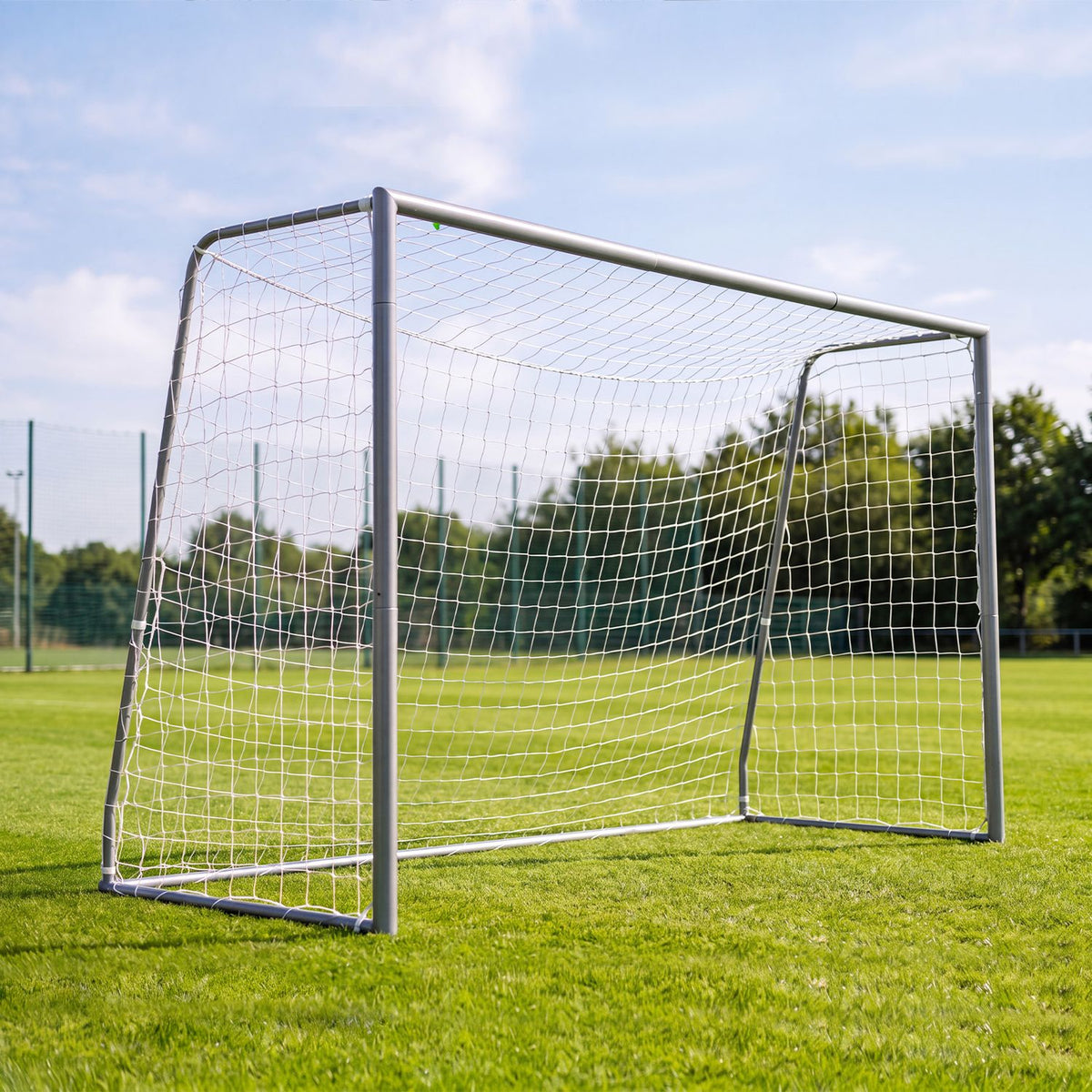 Metal soccer goal with a white net on a sunny grass field.